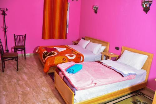 two beds in a room with pink walls at Hotel De La Vallée in Aït Baha