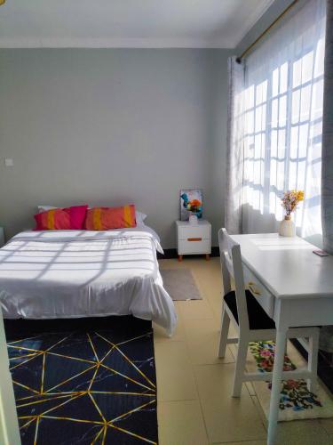 a bedroom with a bed and a table and a desk at Kojik Homes in Ngong in Ngong