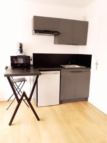 une cuisine avec un comptoir noir et un évier dans l'établissement Le Studio De Gustave, à Lens