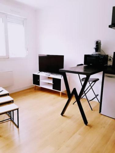 un salon avec une table noire et une télévision dans l'établissement Le Studio De Gustave, à Lens