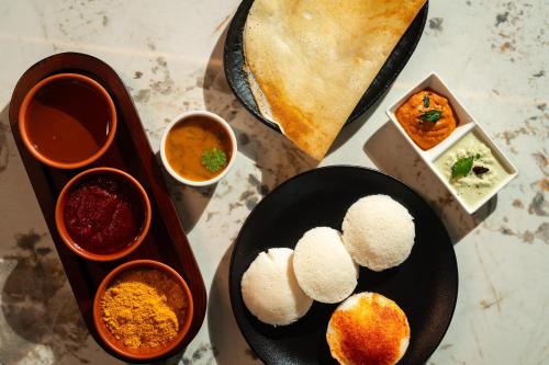 a table with two plates of food and some dipping sauces at The Palomar By Crossway in Chennai