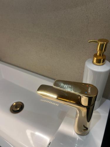 a gold bathroom faucet on a white sink at NOVA LUXURY DESIGN in Zagreb