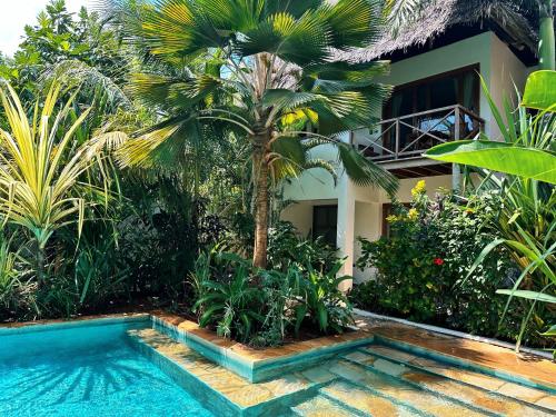a house with a palm tree next to a swimming pool at Maisha Nungwi - Boutique Hotel in Nungwi