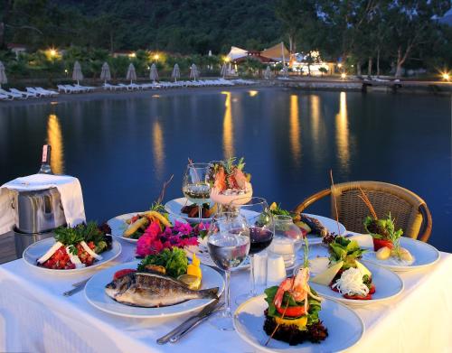 een tafel met borden met voedsel erop naast het water bij Fortezza Beach Resort in Hisarönü