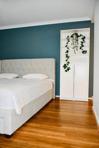 a bedroom with a white bed and a blue wall at Melton Home Stay in Melton