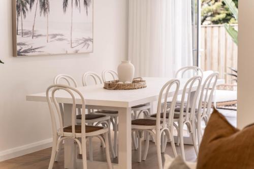 a white dining room table with white chairs at The Hamptons House Kiama in Kiama