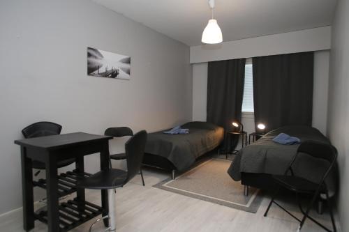 a room with two beds and a table and chairs at Kolmio Kokkola in Kokkola