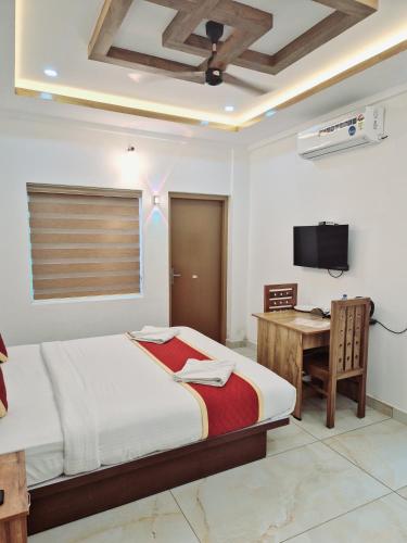 a bedroom with a bed and a desk and a television at MARINA SUITES AIRPORT HOTEL in Cochin