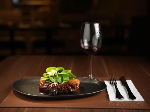 a plate of food and a glass of wine on a table at Grand Mercure Curitiba Rayon in Curitiba