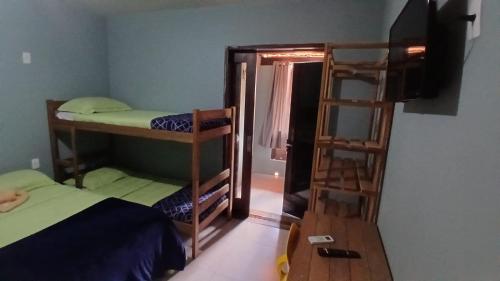 a room with two bunk beds and a television at Maga Inn House - Centro in Blumenau