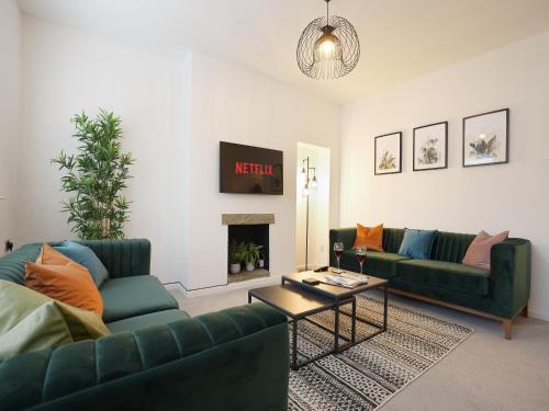a living room with two green couches and a fireplace at The Lodge - comfortable, stylish, 3 bedroom home with 3-6 beds near Utilita Arena - free parking in Sheffield