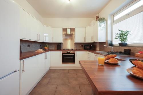 a kitchen with white cabinets and a wooden table at The Lodge - comfortable, stylish, 3 bedroom home with 3-6 beds near Utilita Arena - free parking in Sheffield