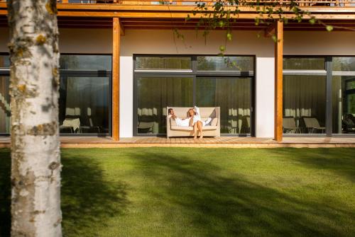 a woman sitting on a couch on the porch of a house at Dolomitengolf Hotel & Spa in Lavant