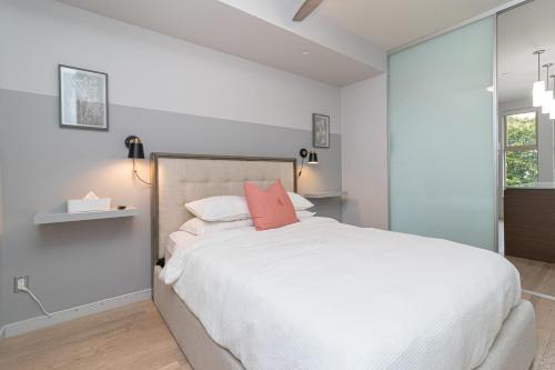 a bedroom with a large white bed with pink pillows at Sleek Kitchen Island And Garden Views in Victoria