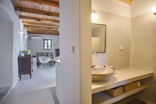 a bathroom with a sink and a counter with a mirror at Elegantly restored traditional cottage in Logothetiánika
