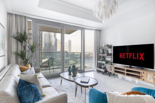 a living room with a couch and a tv at Luxury 2BR Apartment with Stunning Burj Khalifa & Fountain Views - Opera Grand, Downtown in Dubai