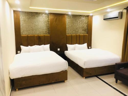 zwei Betten in einem Hotelzimmer mit weißen Laken in der Unterkunft Blue Moon Residency in Islamabad