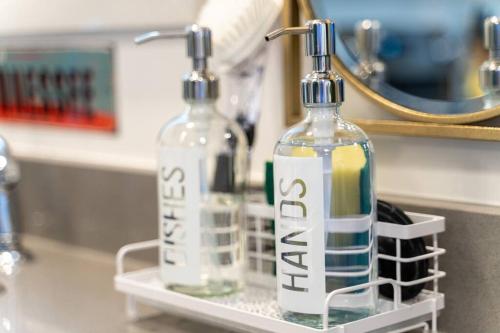 two bottles sitting on a bathroom counter in front of a mirror at New Design-2 Miles to Broadway in Nashville
