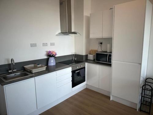 a white kitchen with a sink and a refrigerator at Flat 303 One bedroom apartment in Birmingham