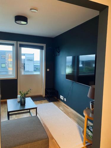 a living room with a blue wall with a tv at Leilighet i Tromsø in Tromsø