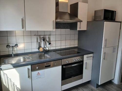 a kitchen with white cabinets and a sink at Ferienwohnungen Viersen in Viersen