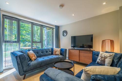 a living room with blue couches and a flat screen tv at The Smelting Pot in Backbarrow