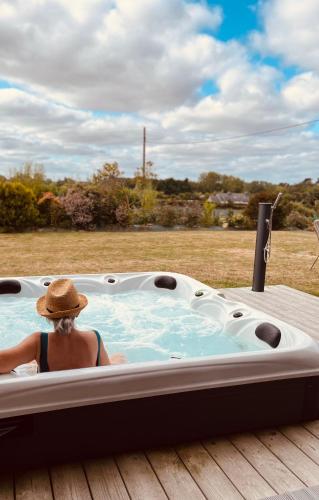 a woman sitting in a jacuzzi tub on a deck at LES ROMARINS gite 4 étoiles in Pleubian