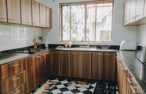 eine Küche mit Holzschränken und Spüle und einem Fenster in der Unterkunft Arusha Kwetu Villa in Sokon