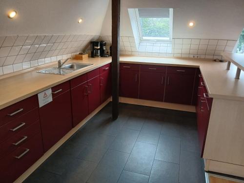 a kitchen with red cabinets and a sink and a window at Ferienwohnungen Viersen in Viersen