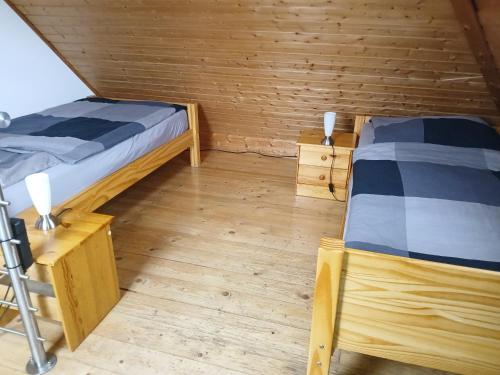 two beds in a room with wooden walls and wooden floors at Ferienwohnungen Viersen in Viersen