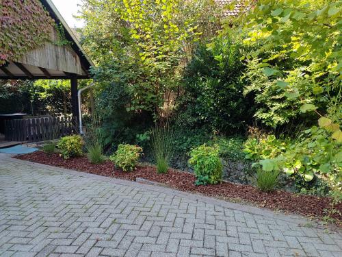 a garden with plants and a brick driveway at WOLFSHÖHLE Schwarzwald-Apartment in Achern