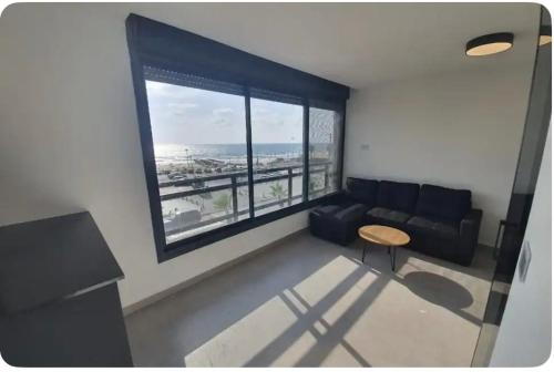 a living room with a couch and a table and a window at Ryo 11 דירת נופש חדשה על חוף הים נוף לים in Bat Yam