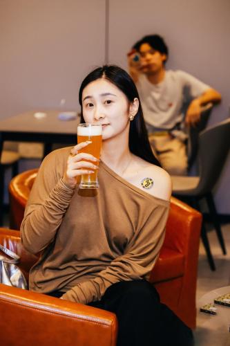 a woman sitting in a chair holding a glass of beer at Dayin Youth Hostel - Old Town & People's Square& Rail Hub -Social Area -Bar -Café -Gym -Free Laundry Luggage Storage -24H Front Desk -English Service in Shanghai