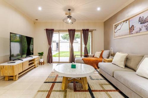 a living room with a couch and a tv at Morden Elegant 4 Bedroom House in Broadview