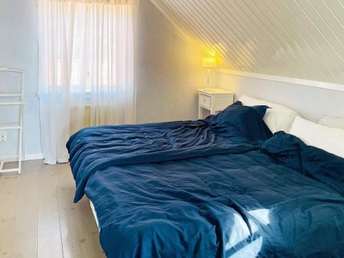 a bed with a blue comforter in a bedroom at 4 star holiday home in KYRKESUND in Kyrkesund