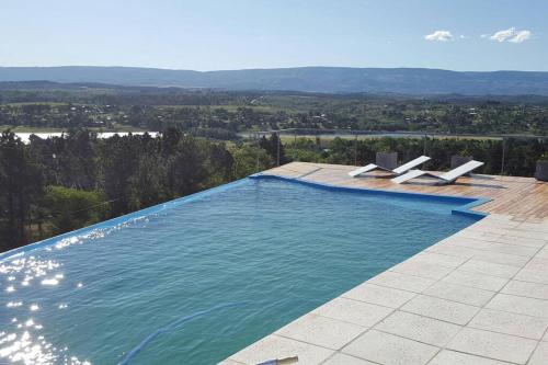 a swimming pool with chairs and a view of the mountains at Dique Los Molinos Exclusiva casa vista al lago in Cordoba