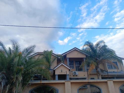 a house with palm trees in front of it at Manasseh Bed & BreakFast Gabs North in Kgaphamadi
