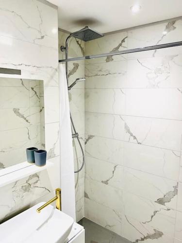 une salle de bain blanche avec une douche et un lavabo dans l'établissement Le Chic Proche centre avec parking, à Grenoble