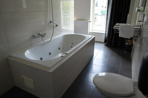 a white bathroom with a tub and a toilet at 1851 Bar - Hotel - Cinema in Wijk bij Duurstede