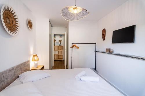 une chambre avec un lit blanc et une télévision à écran plat dans l'établissement Superbe 2 Pièces Rénové Grande Terrasse et Vue Mer, à Cagnes-sur-Mer