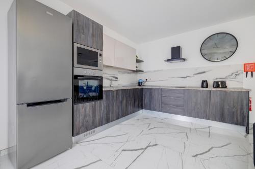 a kitchen with a refrigerator and a clock on the wall at Chic Apartment Stays in Il-Gżira