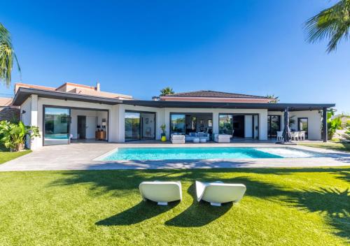 une villa avec une piscine et deux chaises dans l'établissement La Californienne - Villa contemporaine design, à Sauvian
