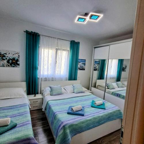 a bedroom with two beds with blue curtains and mirrors at Apartment Radalj in Kaštela