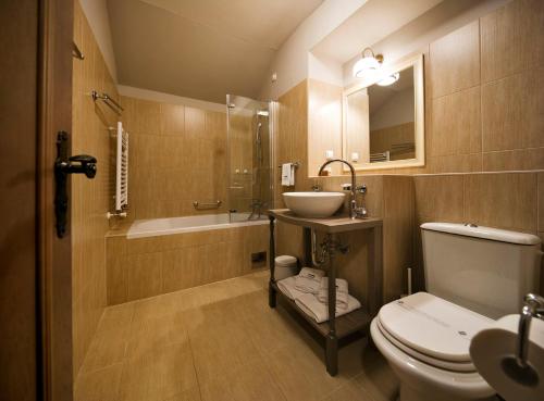 a bathroom with a toilet and a sink and a tub at Hotel Jägerhorn in Zagreb