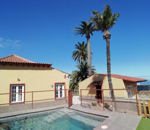 a house with a swimming pool and palm trees at Finca Las Tapias, Casa Mañé in Puerto de la Cruz