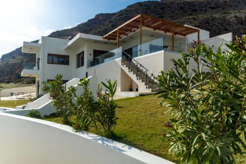 a white house with a mountain in the background at Beachfront Villa Atalandia with Heated Pool, Gym, BBQ & Office in Goúdhouros