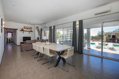 a dining room and living room with a table and chairs at Villa in San Antonio sleeps 10 in Ses Paisses