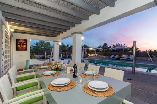 a dining table and chairs on a patio with a pool at Villa in San Antonio sleeps 10 in Ses Paisses