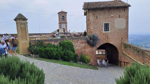 a brick building with a clock tower on a hill at Casa Nonna Ada in Cisterna dʼAsti