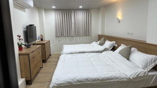 a bedroom with two white beds and a television at Fulong City B&B in Yilan City